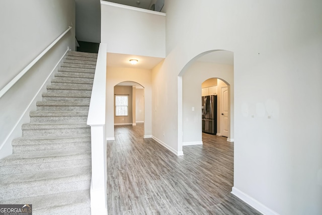 stairway with hardwood / wood-style floors and a high ceiling