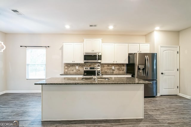 kitchen with stainless steel appliances, dark wood-type flooring, sink, white cabinets, and an island with sink