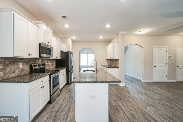 kitchen with white cabinets, sink, an island with sink, wood-type flooring, and stainless steel appliances