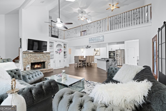 living room featuring beamed ceiling, dark hardwood / wood-style flooring, a fireplace, and high vaulted ceiling