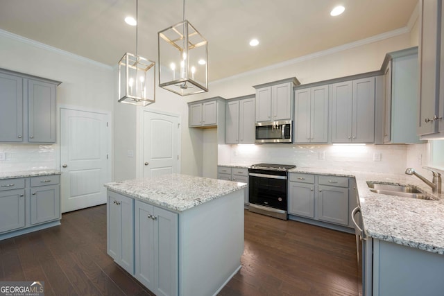 kitchen with sink, dark hardwood / wood-style floors, decorative light fixtures, a kitchen island, and appliances with stainless steel finishes