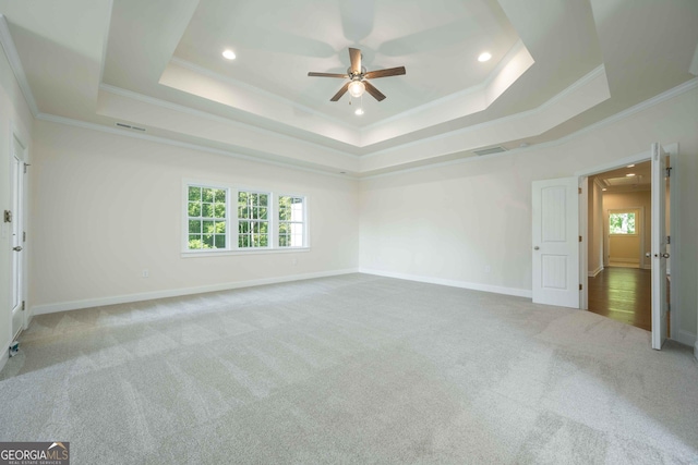 unfurnished room featuring ceiling fan, a raised ceiling, crown molding, and light carpet