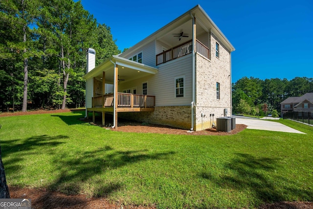 rear view of property featuring central air condition unit, ceiling fan, and a yard