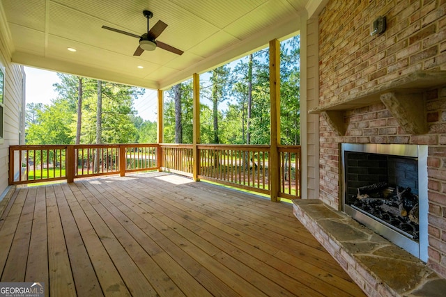 wooden deck featuring ceiling fan and a fireplace