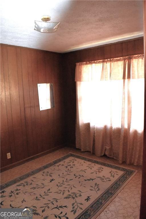 unfurnished room with a textured ceiling and wood walls