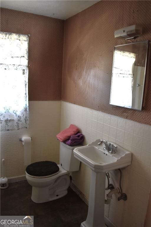 bathroom featuring tile walls and toilet