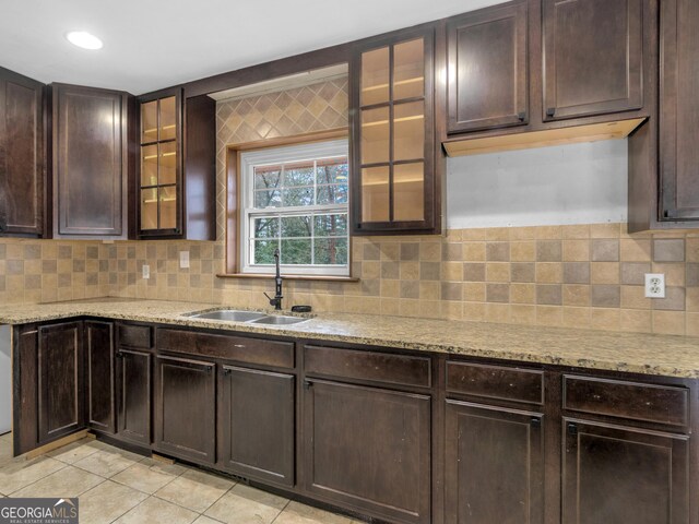 kitchen featuring light stone counters, light tile patterned floors, sink, and dark brown cabinetry