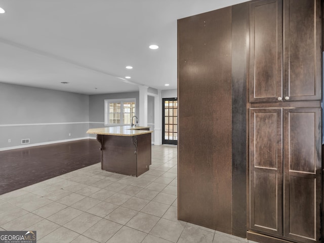 kitchen with a breakfast bar, a center island with sink, and light tile patterned floors