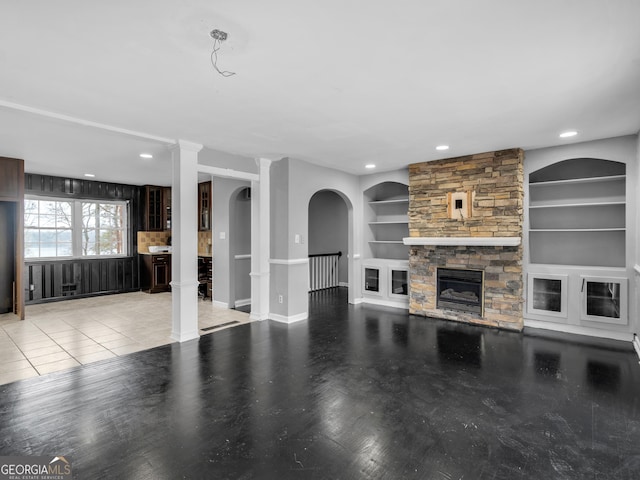 unfurnished living room featuring a fireplace, built in shelves, and light tile patterned floors