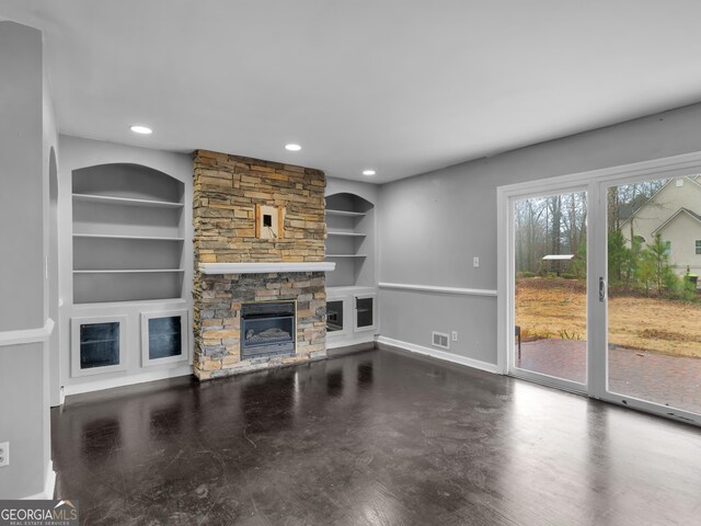 unfurnished living room featuring built in shelves and a stone fireplace