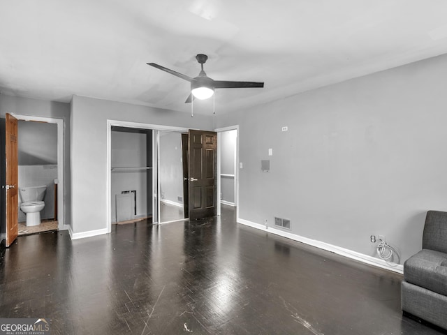 unfurnished bedroom featuring connected bathroom, a closet, ceiling fan, and dark wood-type flooring