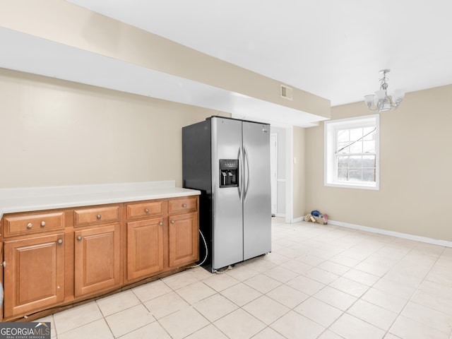 kitchen with a chandelier, stainless steel refrigerator with ice dispenser, and light tile patterned flooring