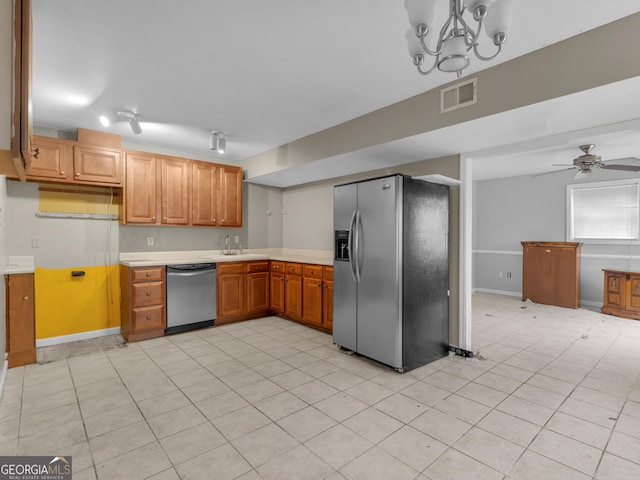 kitchen with sink, stainless steel appliances, track lighting, light tile patterned floors, and ceiling fan with notable chandelier