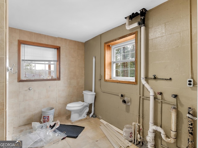 bathroom featuring tile patterned flooring, toilet, and tile walls