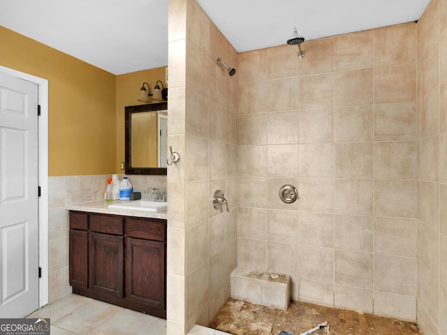 bathroom with tile patterned floors, vanity, a tile shower, and tile walls