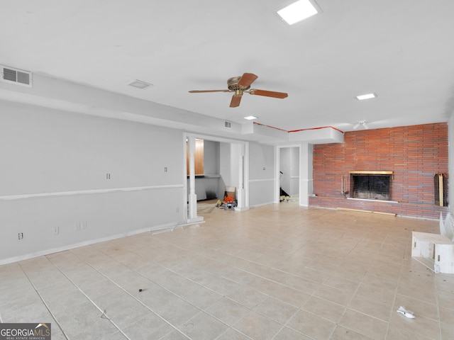 unfurnished living room featuring ceiling fan, light tile patterned floors, and a brick fireplace