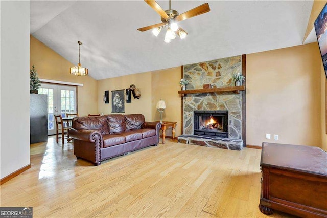 living room with high vaulted ceiling, french doors, ceiling fan with notable chandelier, a stone fireplace, and light hardwood / wood-style floors