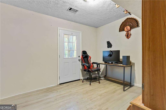 office area with light hardwood / wood-style floors and a textured ceiling