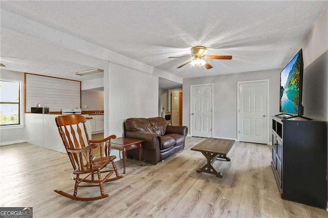 living room featuring a textured ceiling, light hardwood / wood-style flooring, and ceiling fan