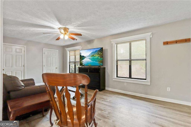 interior space with ceiling fan, a textured ceiling, and light hardwood / wood-style flooring