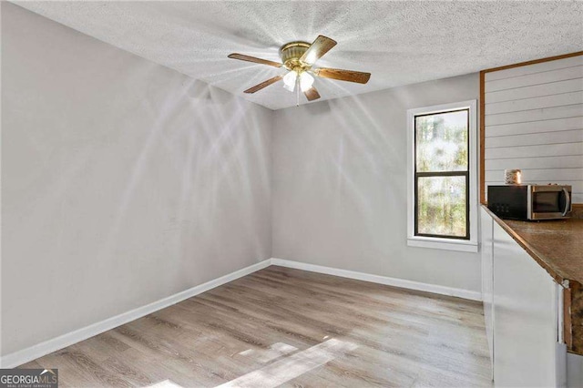 spare room with a textured ceiling, light wood-type flooring, and ceiling fan