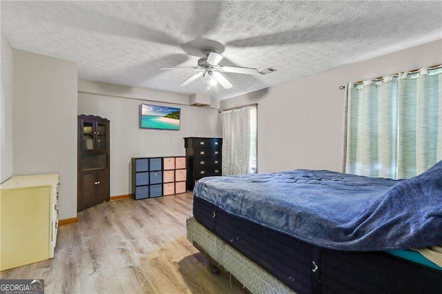 bedroom featuring a textured ceiling, light hardwood / wood-style flooring, and ceiling fan