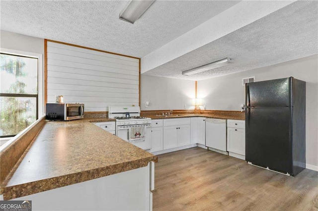 kitchen with white cabinetry, sink, light hardwood / wood-style floors, a textured ceiling, and white appliances