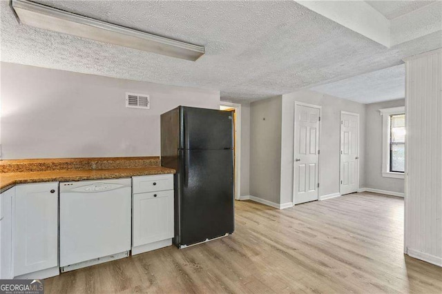 kitchen with light wood-type flooring, white dishwasher, black fridge, and white cabinetry