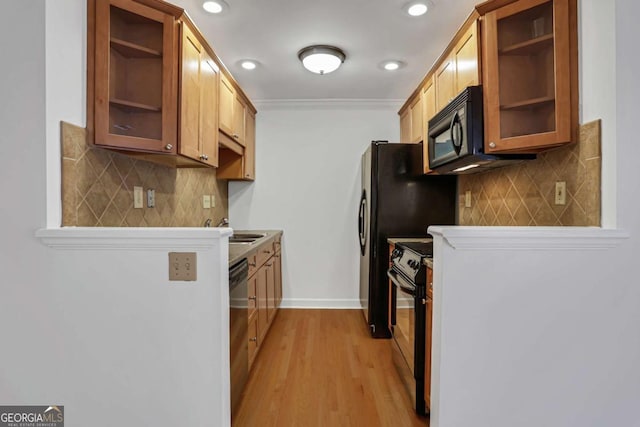 kitchen with black appliances, decorative backsplash, crown molding, and light hardwood / wood-style flooring