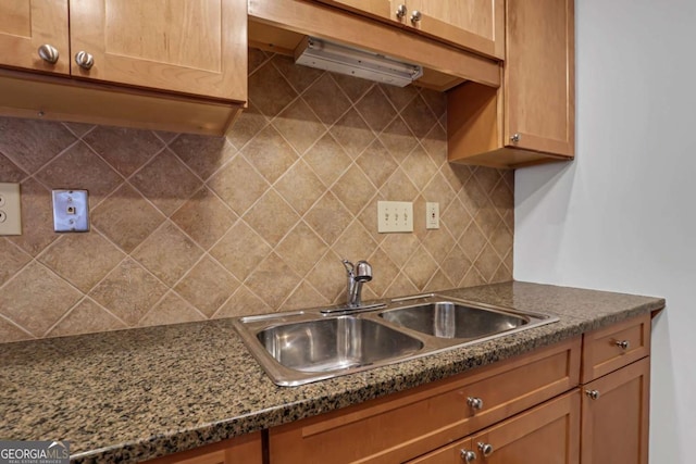 kitchen featuring dark stone countertops, sink, and backsplash