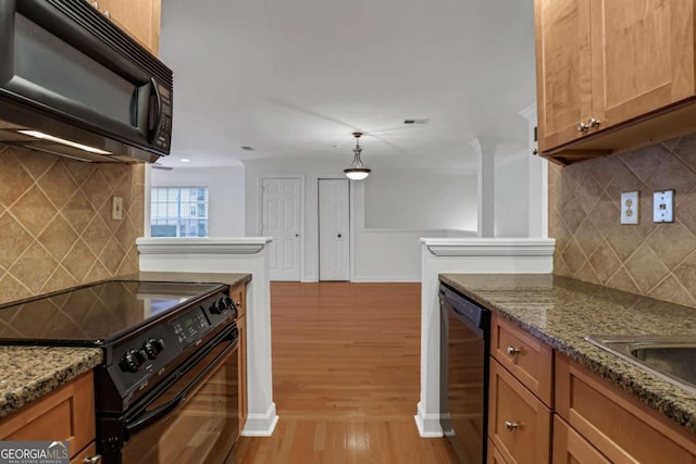 kitchen featuring black appliances, dark stone countertops, backsplash, and light hardwood / wood-style flooring