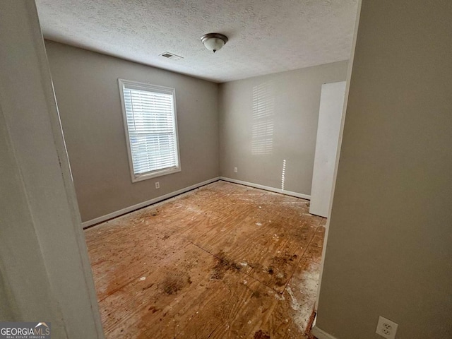 empty room featuring a textured ceiling and hardwood / wood-style flooring