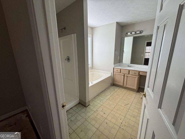 bathroom with plus walk in shower, vanity, and a textured ceiling