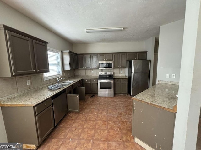 kitchen with backsplash, sink, a textured ceiling, and appliances with stainless steel finishes