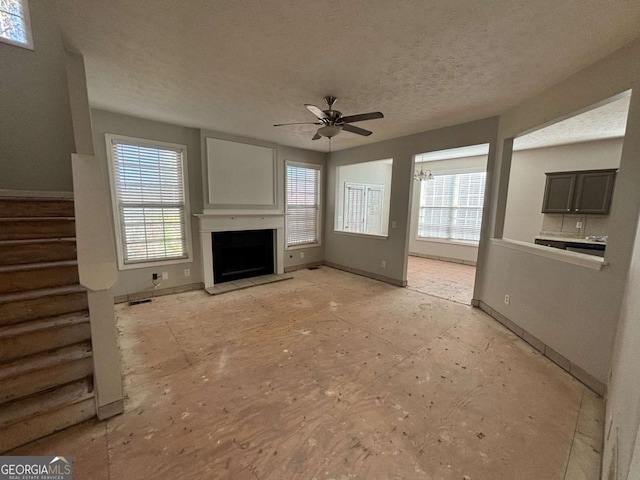 unfurnished living room with ceiling fan and a textured ceiling