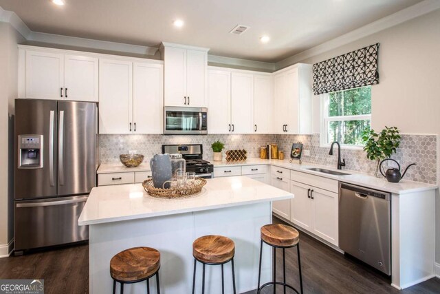 kitchen with white cabinets, sink, dark hardwood / wood-style floors, appliances with stainless steel finishes, and a kitchen island