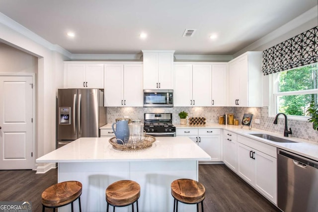 kitchen featuring dark hardwood / wood-style flooring, sink, a kitchen island, and appliances with stainless steel finishes