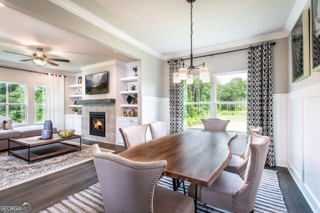 dining space featuring built in shelves, plenty of natural light, ceiling fan with notable chandelier, and dark hardwood / wood-style floors