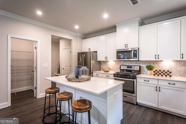 kitchen with white cabinets, a center island, stainless steel appliances, and dark wood-type flooring