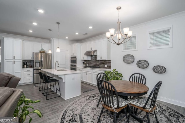 dining area with crown molding, wood-type flooring, sink, and a chandelier