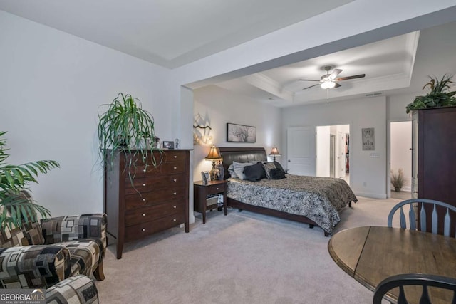 bedroom featuring light colored carpet, a raised ceiling, and ceiling fan