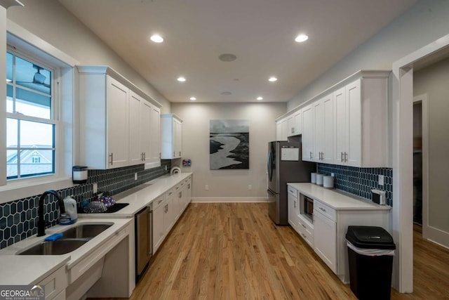 kitchen with decorative backsplash, light hardwood / wood-style floors, white cabinetry, and sink