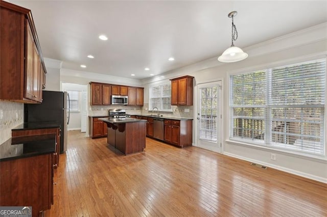 kitchen featuring tasteful backsplash, a center island, stainless steel appliances, and light hardwood / wood-style flooring