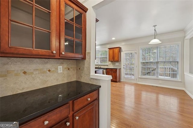 kitchen with pendant lighting, dishwasher, light hardwood / wood-style flooring, ornamental molding, and tasteful backsplash