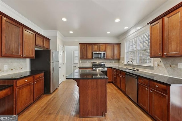 kitchen featuring a center island, sink, ornamental molding, appliances with stainless steel finishes, and light hardwood / wood-style floors