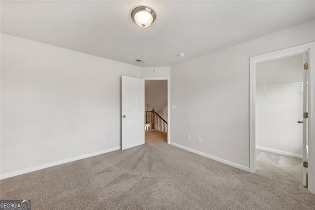 unfurnished bedroom featuring light carpet, a walk in closet, and a closet