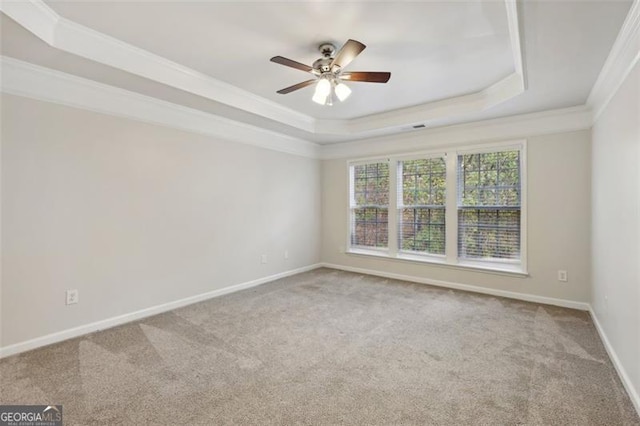 empty room featuring a tray ceiling, ceiling fan, carpet floors, and ornamental molding