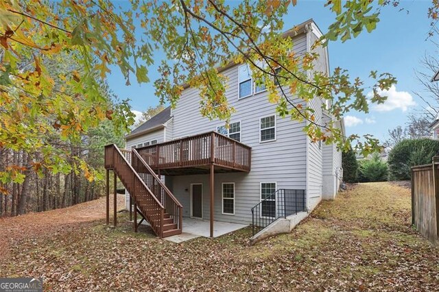 rear view of property featuring a wooden deck and a patio