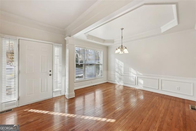 foyer with a tray ceiling, crown molding, an inviting chandelier, and hardwood / wood-style flooring