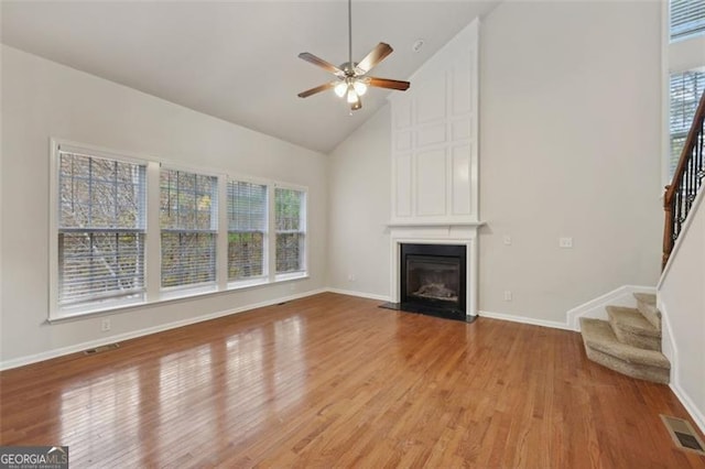 unfurnished living room with ceiling fan, a fireplace, high vaulted ceiling, and light hardwood / wood-style floors